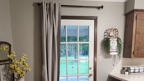 A kitchen with a stone tile floor, a white door with a view to a green yard, a wooden cabinet, and a bar stool area. - The Madison
2 story colonial style home built in 1978, with my father's own hand (Crossett)