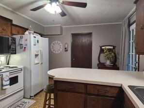 A kitchen with a refrigerator, stove, and a ceiling fan.