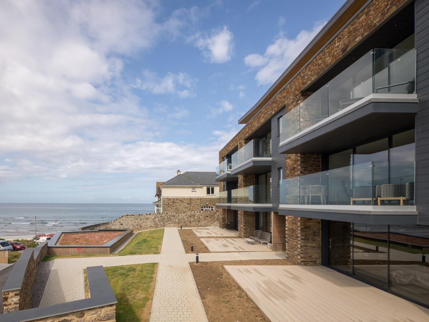 Un bâtiment moderne avec une façade en pierre, de grandes fenêtres et une vue sur la mer.