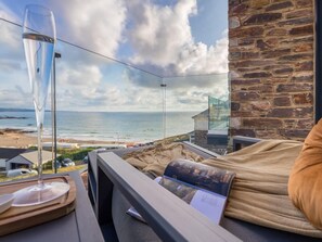 A room with a view of the sea, a glass table with a wine glass, and a magazine. - 2 Bed in Bude (oc-92484) (Bude)