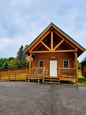 A log cabin with a porch, a door, and windows. - Blisspoint Munising (Munising)