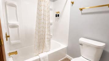 A bathroom with a bathtub, toilet, and shower curtain.