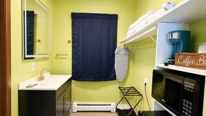 A compact kitchen with a sink, a microwave, a coffee maker, and a hanging rack. - Blisspoint Munising (Munising)