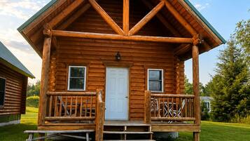 A log cabin with a porch, a front door, and two windows.