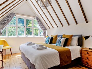 A bedroom with a large bed, a window with curtains, a wooden ceiling, and a desk with a chair. - 3 Bed in Dorchester (oc-92415) (West Dorset District)