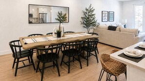 Un espace repas moderne avec une table en bois, des chaises noires et une cuisine en arrière-plan.