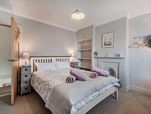 Ein Schlafzimmer mit Bett, Nachttischen, einem Kleiderschrank, einer Hängeleuchte und einem Kamin.