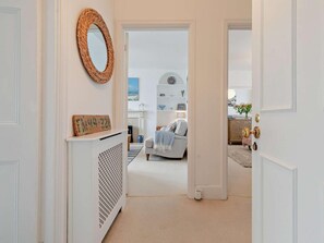 Ein Flur, der zu einem Schlafzimmer mit Bett, Kommode und Spiegel führt.