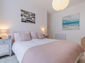 Ein Schlafzimmer mit einem Bett, zwei Nachttischen, einer Lampe, einem Gemälde und einer Heizung.