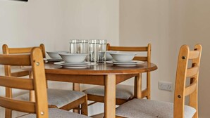 Une table de salle à manger ronde en bois, accompagnée de six chaises, chacune dotée d’un siège rembourré.