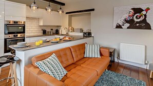 Una cocina moderna con una isla central, un sofá con cojines estampados y una obra de arte en la pared.