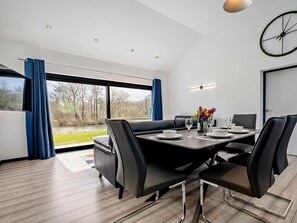 Ein stilvolles Esszimmer mit einem großen Tisch, schwarzen Stühlen und Blick auf einen Fluss.