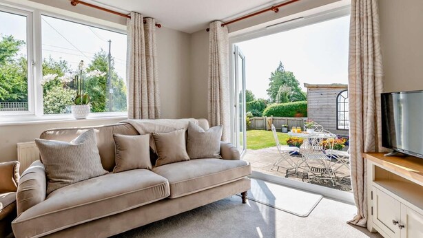 Ein Wohnzimmer mit Sofa, Fernseher und Blick ins Freie.