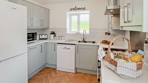 Eine moderne Küche mit weißen Schränken, einem Toaster, einer Kaffeemaschine und einem Fenster mit einem 'welcome'-Schild.