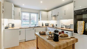 Een moderne keuken met witte kasten, een houten eiland en diverse apparaten.
