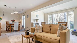 Een gezellige woonkamer met een bank, een salontafel en een eethoek met stoelen en een tafel.