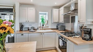 A modern kitchen with white cabinets, a gas stove, a microwave, and a sink. - 2 Bed in Matlock (oc-92639) (Holloway)