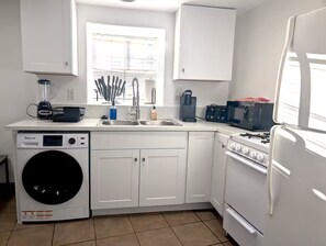 A compact kitchen with a washing machine, a stove, a microwave, and a sink. - Downtown District - Modern Apt Yard, King Bed, W/D (Albuquerque)