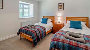 Une chambre avec deux lits, une fenêtre, un radiateur et un luminaire au plafond.
