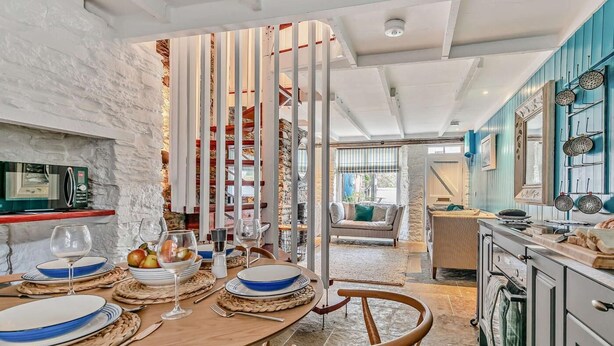 A modern kitchen with a dining area, stone walls, and a view to the living room. - 3 Bed in Fowey (oc-92548) (Fowey)