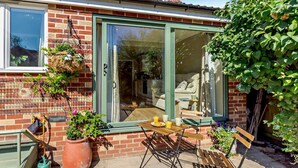 A patio with a table and chairs, a potted plant, and a sliding glass door leading to an interior space with a sofa and a dining table. - 1 Bed in Harrogate (oc-92519) (Harrogate)