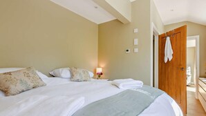A bedroom with a large bed, a nightstand with a lamp, and a wooden door. - 1 Bed in Harrogate (oc-92519) (Harrogate)