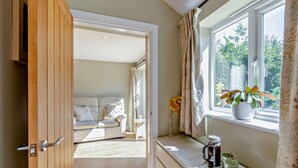 A room with a wooden door, a window with curtains, a plant on the windowsill, and a table with a coffee pot and cups. - 1 Bed in Harrogate (oc-92519) (Harrogate)