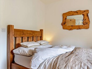 Ein Bett mit hölzernem Kopfteil, zwei Kissen und einer gemusterten Decke.