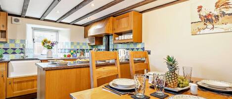 A kitchen with wooden cabinets, a tiled backsplash, and a dining area set for a meal.
