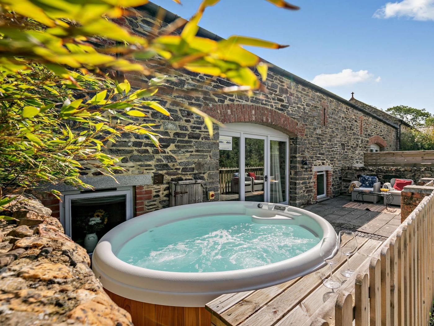 Edificio de piedra con jacuzzi y zona de estar al aire libre.