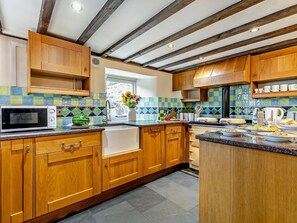 A kitchen with wooden cabinets, a microwave, a sink, and a window with a view.