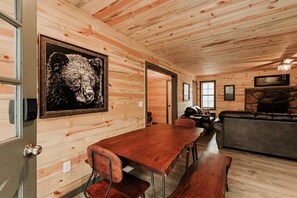 A wooden interior with a dining table, benches, a sofa, and a fireplace. - Dog Friendly 2bd/2bth family friendly hot tub (Sevierville)
