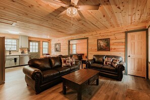A log cabin interior with two leather sofas, a wooden coffee table, and a dining table. - Dog Friendly 2bd/2bth family friendly hot tub (Sevierville)