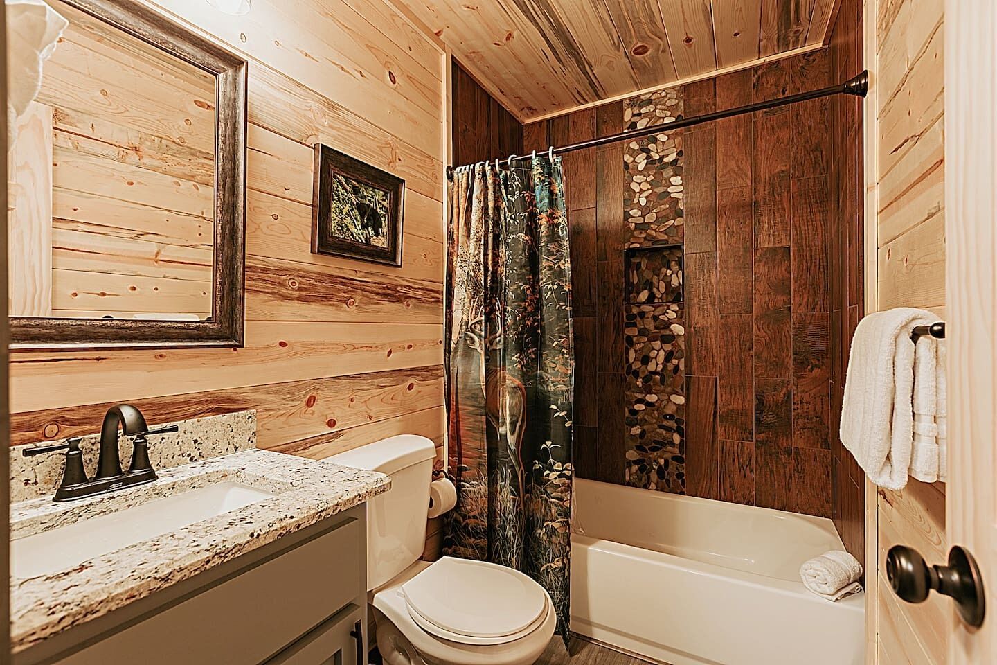 A bathroom with wooden walls, a sink, toilet, and bathtub.