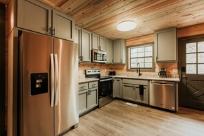 A kitchen with stainless steel appliances, light-colored cabinets, a granite countertop, and a wooden ceiling. - Dog Friendly 2bd/2bth family friendly hot tub (Sevierville)