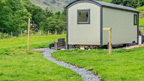 A small, single-story building with a window and a door, surrounded by a grassy area and a gravel path. - 1 Bed in Penrith (oc-92641) (Deepdale)