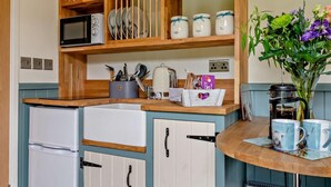 A compact kitchen with wooden cabinets, a microwave, a kettle, and a coffee maker. - 1 Bed in Penrith (oc-92641) (Deepdale)