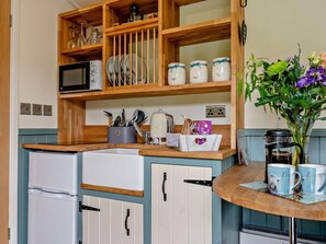 A compact kitchen with wooden cabinets, a microwave, a kettle, and a coffee maker. - 1 Bed in Penrith (oc-92641) (Deepdale)