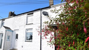 A white building with a door, windows, and a satellite dish. - 2 Bed in Pwllheli (oc-92561) (Llithfaen)