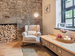 Una habitación acogedora con pared de piedra, una silla, una mesa de madera con velas y un ventanal con vistas.
