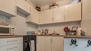 Een keuken met witte kastjes, een magnetron, een fornuis en een vloer met een patroon.