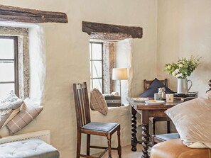 Une pièce chaleureuse avec une chaise en bois, une table avec une lampe et une fenêtre donnant sur un beau paysage.