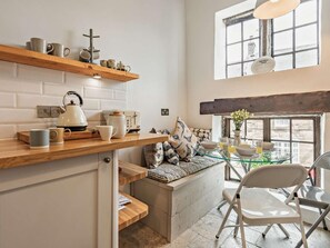 Une cuisine avec un plan de travail en bois, une bouilloire, un grille-pain et une fenêtre donnant sur un immeuble.