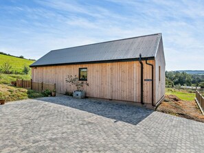 En træbygning med et metal tag, en belagt indgang og et skilt med teksten 'Nellon Lodge'.