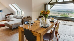 Ein modernes Schlafzimmer im Loft-Stil mit Essbereich, großen Fenstern und Blick auf die Landschaft.