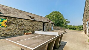 Un bâtiment en pierre avec une longue table et des bancs, probablement un espace communautaire.