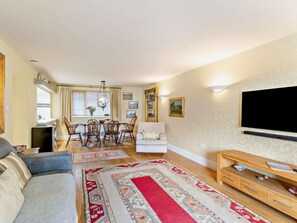 A living room with a sofa, a TV, a dining area with chairs and a table, and a patterned rug. - 2 Bed in Keswick (oc-92600) (Keswick)