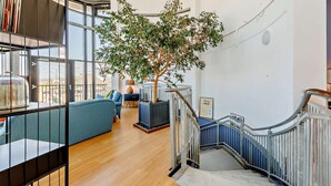 Un ambiente ampio con una scala, un albero grande e un divano blu.