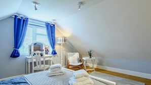 Um quarto com cama, escrivaninha, cadeira e abajur.