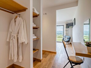 Ein modernes Interieur mit Holzboden, einer Sitzecke mit Stuhl und Tisch und Blick durch eine Glastür.